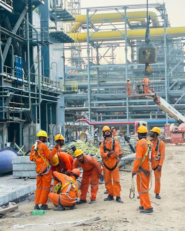 A construction crew in coveralls and hard hats at an industrial site