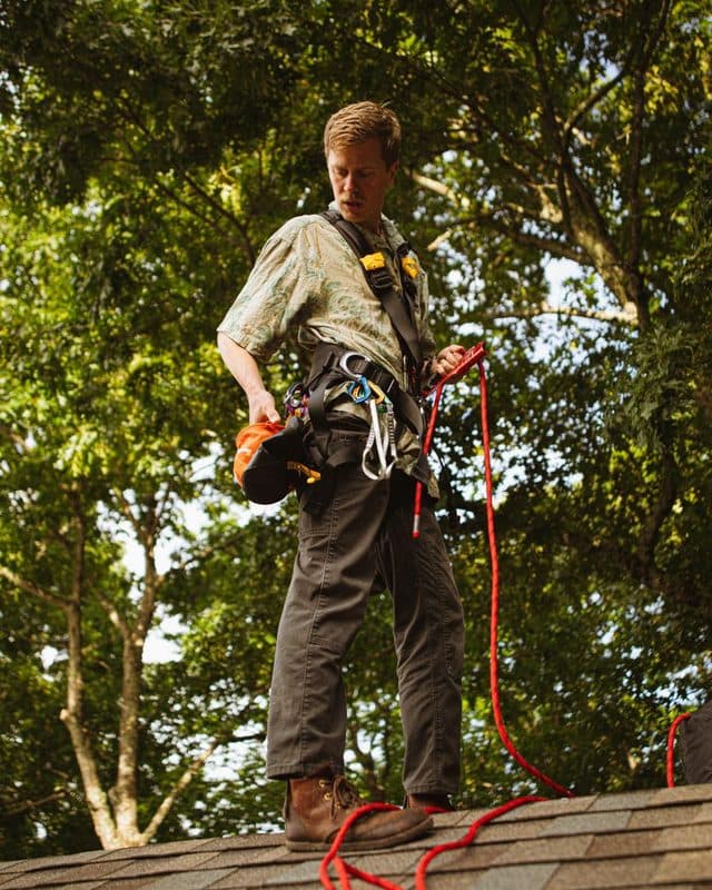 A roofer in a harness checking his lifeline on a pitched roof